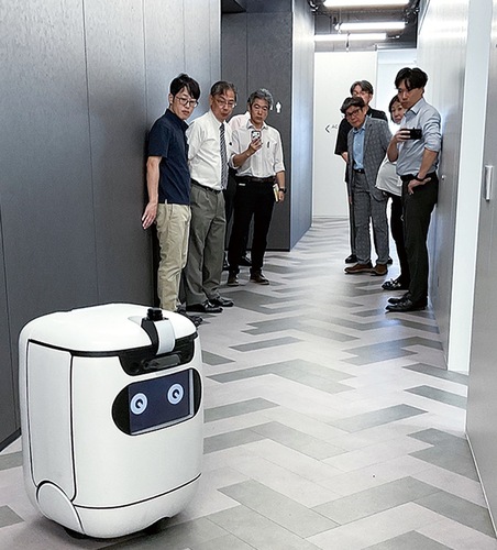 郵便物を担当者に届け終えたライスがメールセンターに戻る様子を興味深く見つめる協議会のメンバー