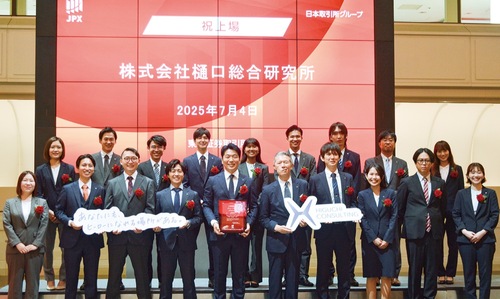 記念撮影に応じる同社スタッフ。前列中央で上場通知書を持つのが樋口社長。静岡県浜松市出身の樋口社長は大学卒業後、証券会社に勤務したのち、起業した