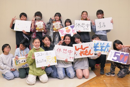 作成したポスターや看板を手に笑顔を見せる子ども店長