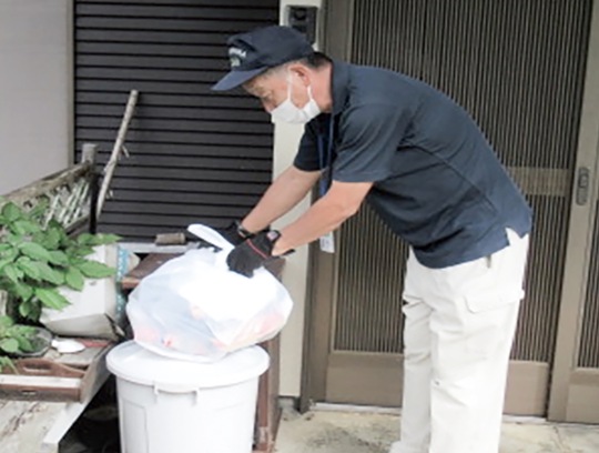 玄関先に出されたごみを収集する職員