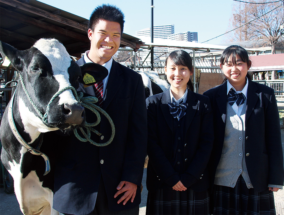 相原高校で、飼育する乳牛と一緒に撮影。左から角田さん、塗井さん、吉川さん=1月19日