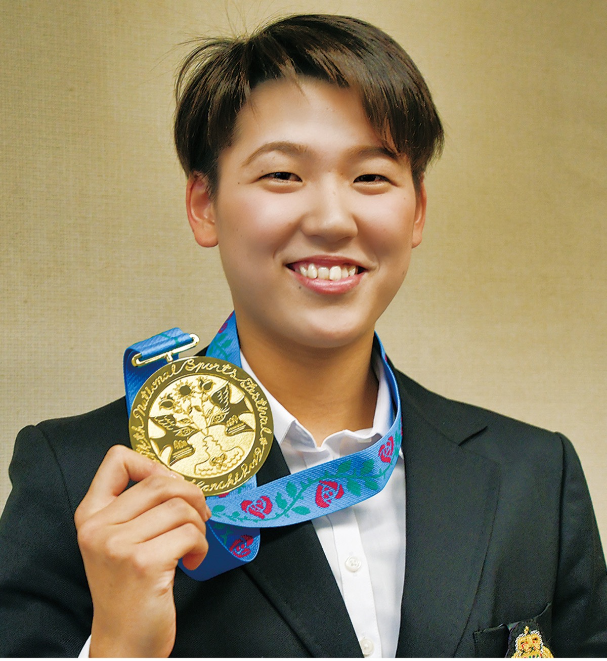 国民体育大会で獲得した金メダルを手に微笑む小堀さん＝11月21日、市役所