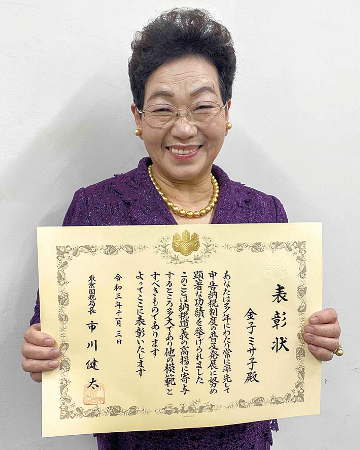 表彰状を手に笑顔を見せる金子さん=11月12日