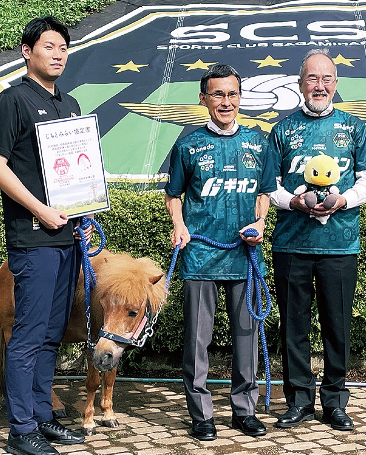 （左から）西谷代表、ひづめで調印したポニー、熊坂常務理事、村松代表理事