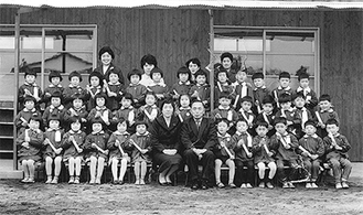 写真上：「1962年（昭和37年） 第１回卒園式」の記念写真。最前列中央左が井鍋初代園長、最後列の１番左が石立元主任。当時は園内に井鍋さんの自宅があり、２歳の櫻井現園長と園児たちが楽しく遊んでいたという（提供写真）