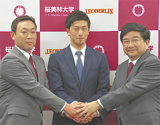 川相拓也さん（中央）と握手する三谷高康学長（右）、津野裕幸監督（左）