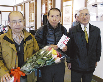 バラの花束を贈る山崎凱史館長（右）と矢萩公男代表（左）＝町田市提供