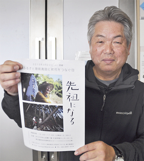 会場前で上映チラシを掲げる武田恒男代表。「力が湧きあがる映画。避難者に力をもらってほしい」と呼びかける