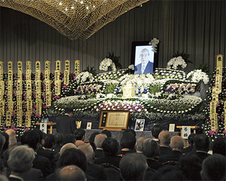 花に囲まれた遺影前に弔辞を読む石阪丈一市長