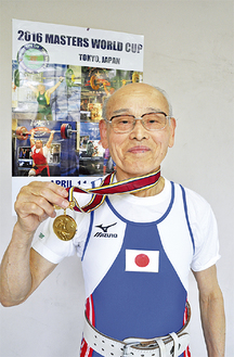 ユニフォームを着用し金メダルを掲げる水村さん（25日・トレーニングする総合体育館で）