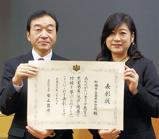 表彰状を掲げる仙北屋校長（左）と学習支援ボランティアコーディネーターの関根美咲さん