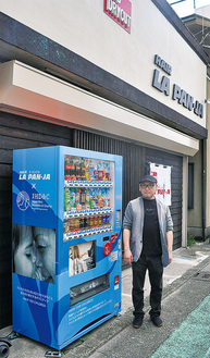 店頭に設置した募金機能を持つ自動販売機と長谷川代表