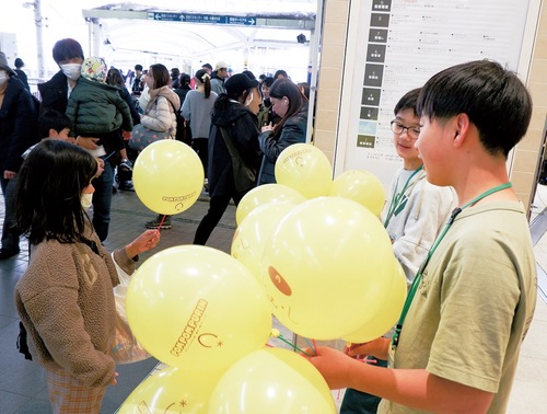 来店客に風船を配布する児童ら