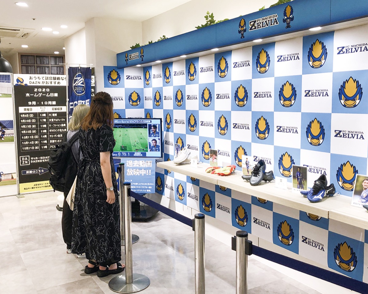 ブースに飾られた選手のスパイクを眺める来場者