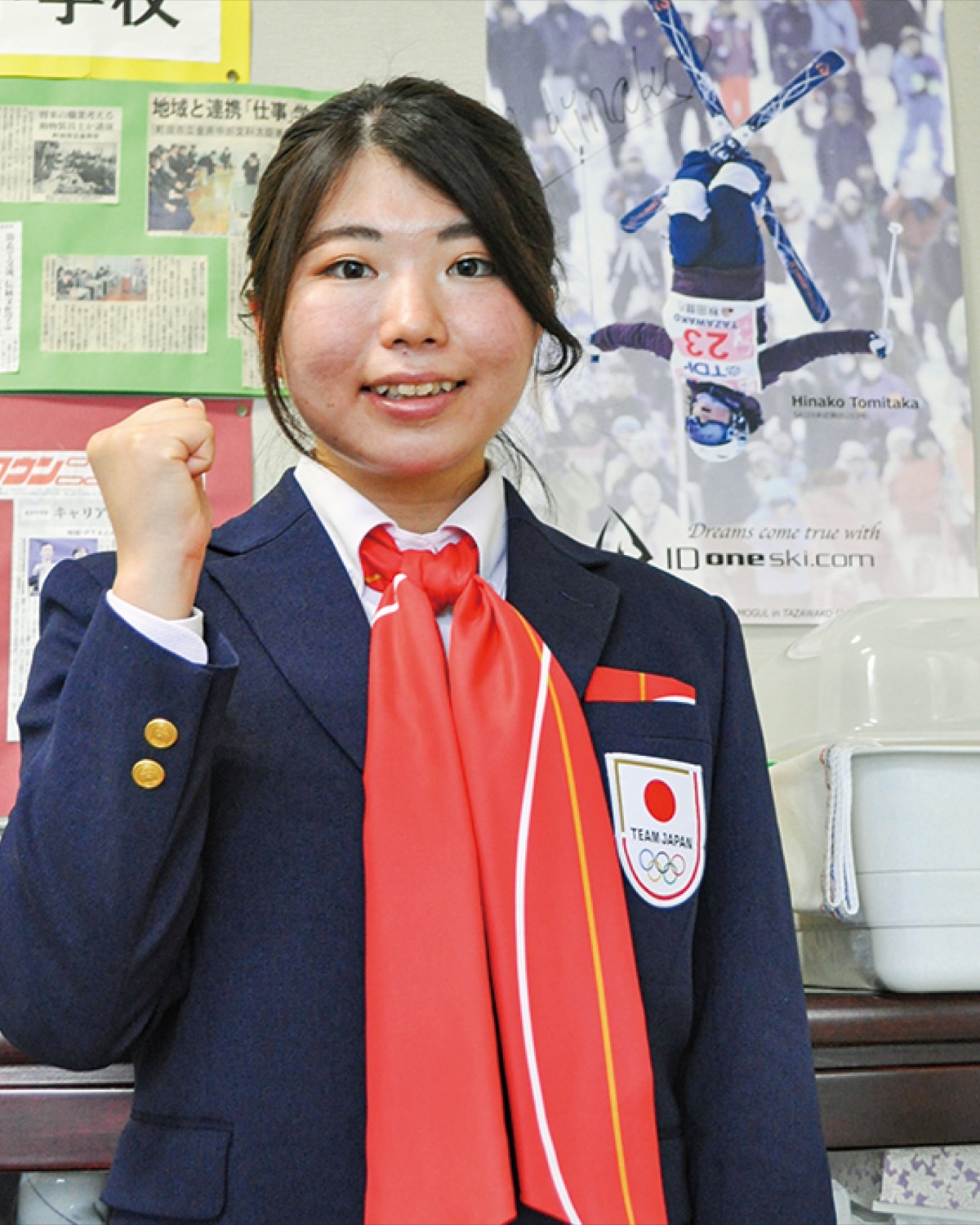 校長室に貼られた自分のポスターの前に立つ冨高さん