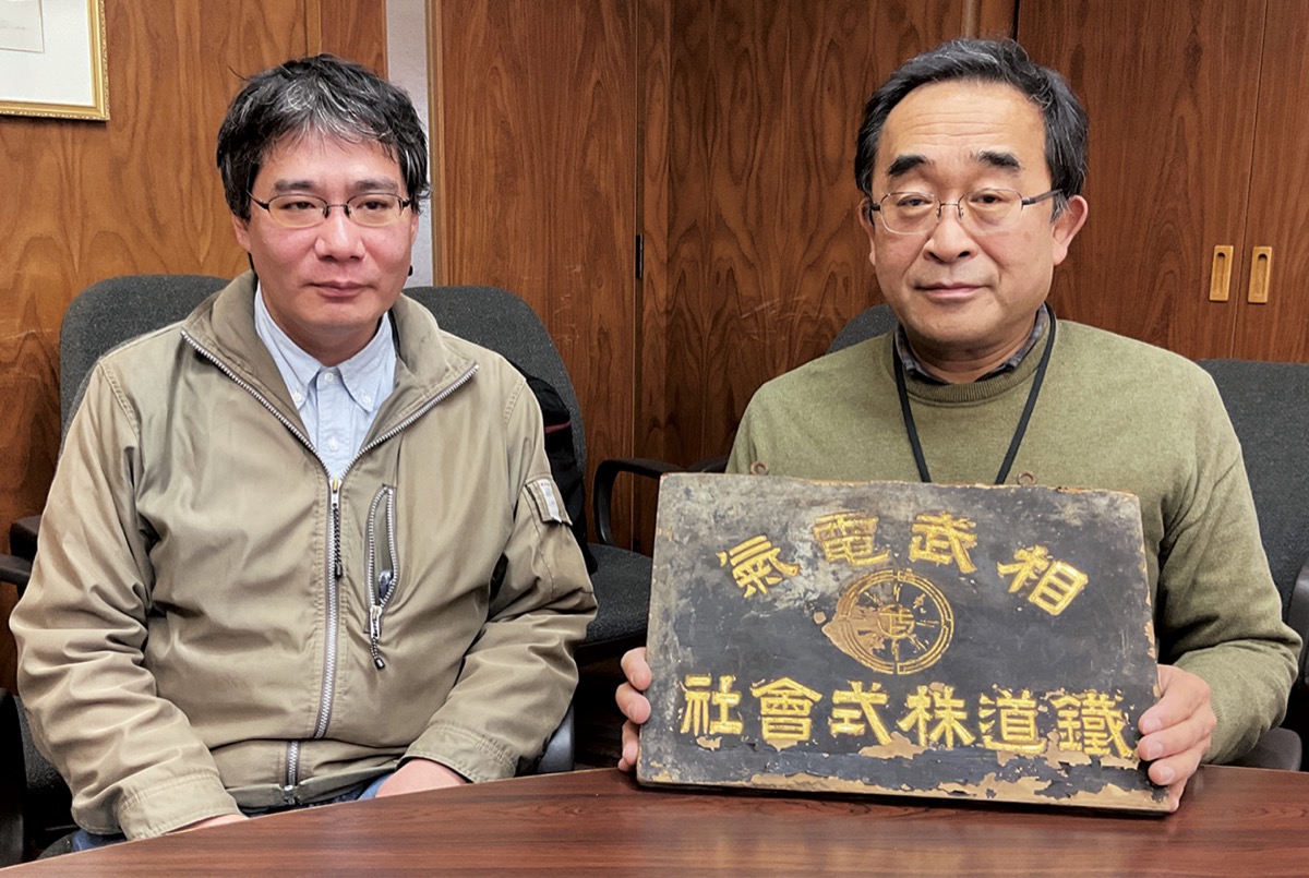 豊島さん（左）と社名板を持つ佐藤さん