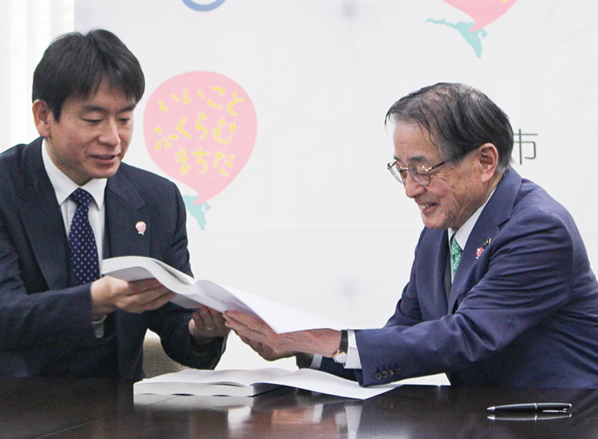 稲垣新市長（左）と引継書について話す石阪氏