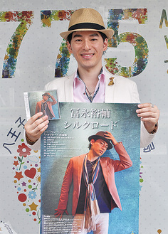 八王子ＦＭの前で、デビューアルバムとポスターを持つ冨永さん