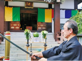 福傳寺で刀を構える伊藤さん。奥に黄色や緑の五色幕が見える