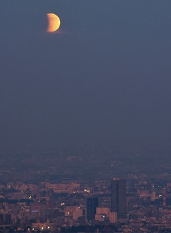 樋口さんが撮影した部分月食＝11月19日午後4時46分頃。下に見える大きなビルはJR八王子駅南口のサザンスカイタワー