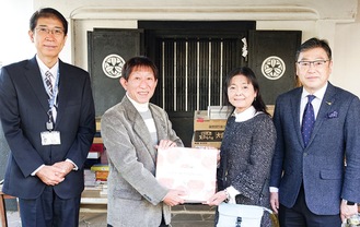 会員自宅で寄贈品を渡す金子会長（左から２人目）と受け取る川久保さん