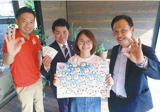 すごろくを持つ委員会メンバー。（左から）芳林健人さん、大塚さん、笠間鈴乃さん、西川垂穂さん