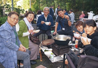 鍋を囲む参加者と斉藤さん（中央右）