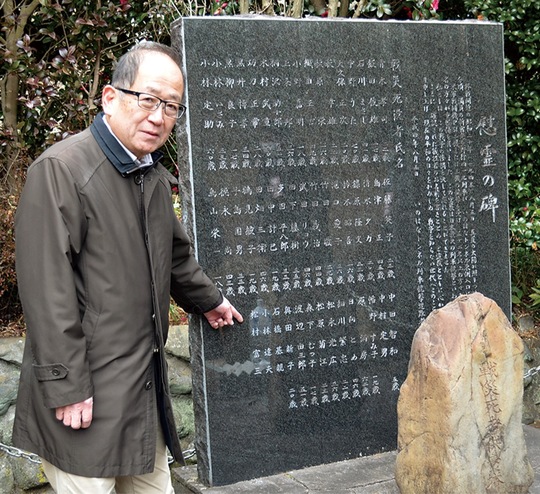 慰霊碑に追加された犠牲者の名前を指し示す齊藤会長
