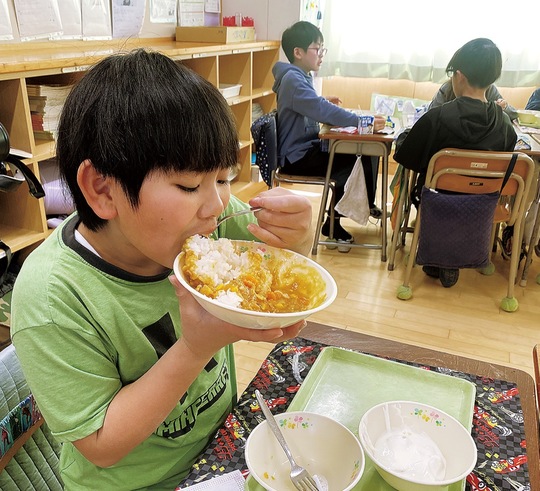 オリジナルカレーを豪快に食べる男子児童