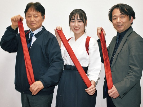 新調した襷を見せる（左から）巻田専務、音渕さん、福井准教授