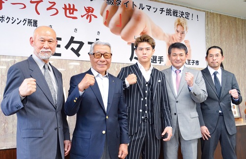 横断幕の前でファイティングポーズを取る佐々木選手（中央）ら
