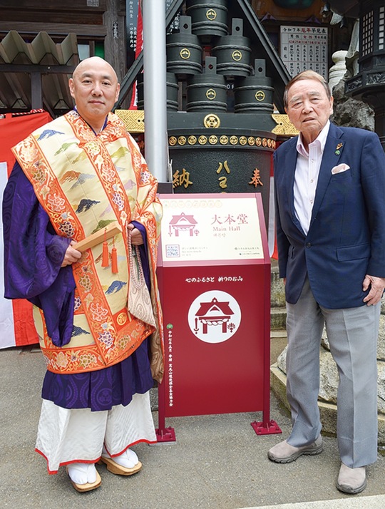 案内板を披露する佐藤貫首（左）と石井会長
