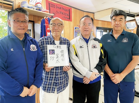 俵積田選手のサインを手にする（株）幼体連スポーツクラブの二宮前理事長、佐藤専務（一番左）ら