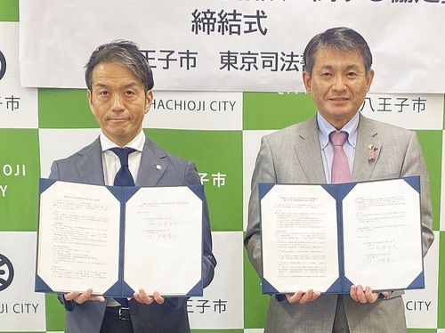 協定締結書を持つ千野会長(左)と初宿市長