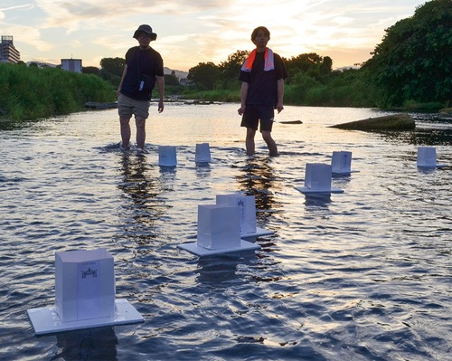 大学生ボランティアらが浅川にとうろうを流した