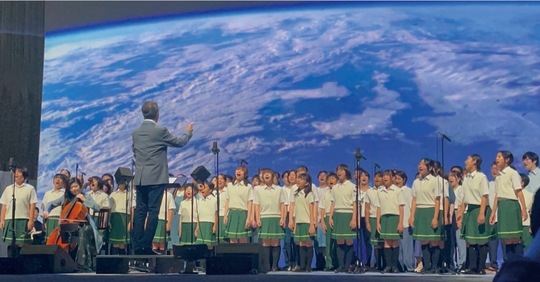 宇宙から送られてきた青い地球の映像をバックに歌い上げた＝はちおうじキッズシンガーズ提供