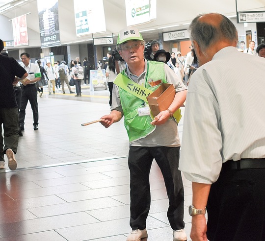 JR八王子駅改札前で扇子を配布する防犯協会員