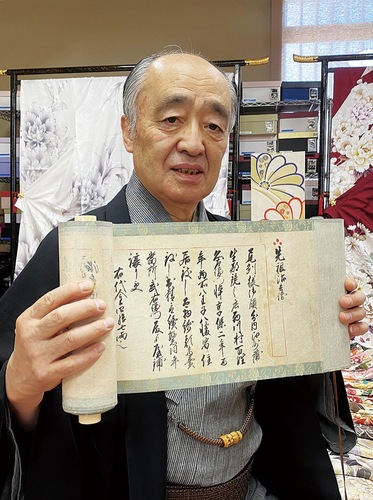 創業年について「享保二年」と書かれた巻物を見せる西川社長