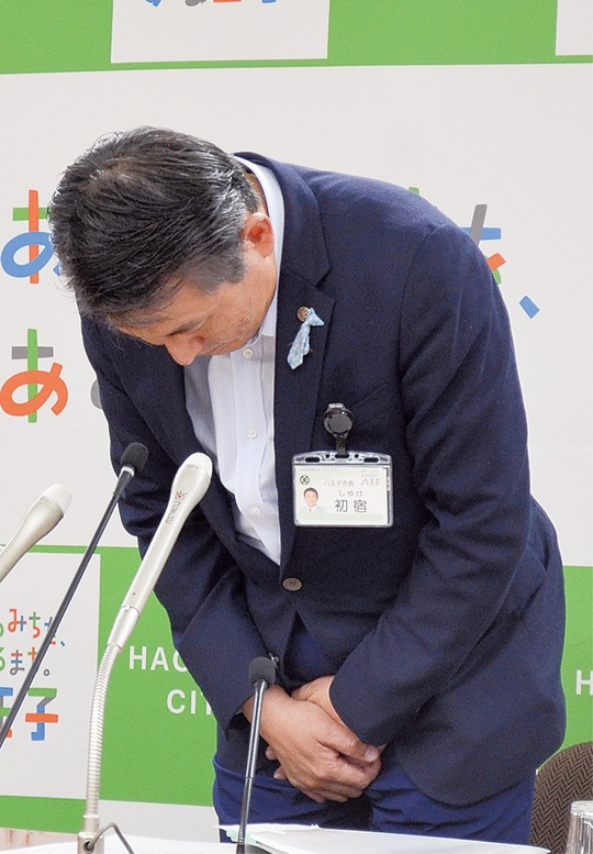記者会見で頭を下げる初宿市長