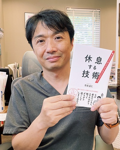 自著『休息する技術』を手にする菅原院長