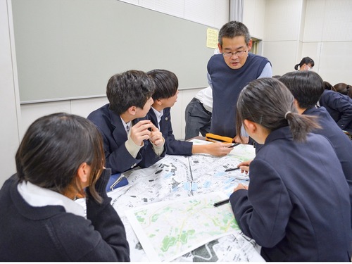 市川さん（写真奥）と南大沢の地図におすすめスポットを書き込む生徒たち