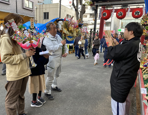 熊手を買い、手締めを贈られる購入客（左）