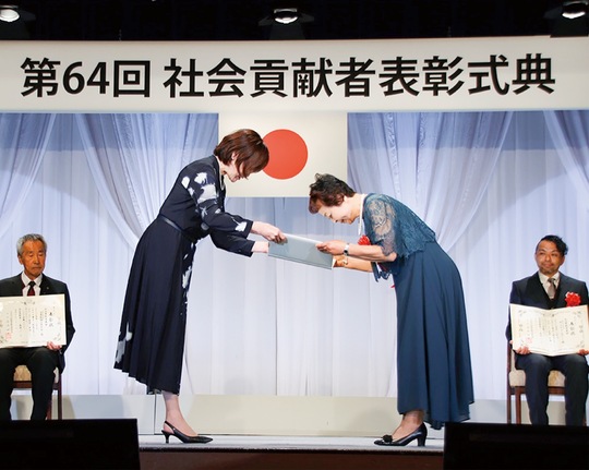 安倍会長から表彰状を受け取る北田さん（中央右）＝同財団提供