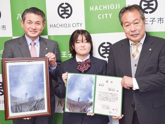 賞状を掲げる籏野さん（中央）と安間教育長（右）、作品を手にする初宿市長