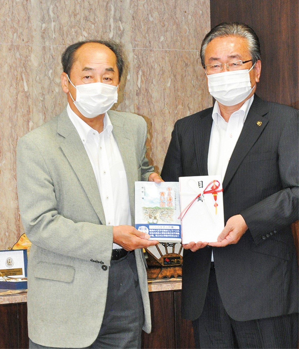 本を手渡す前野さん=左=と石森市長