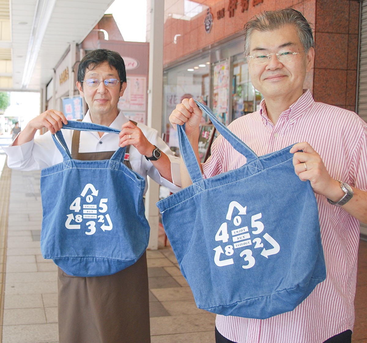 「ロゴの由来をぜひお店の人に聞いてみて」とエコバックを持つ坂口会長（右）と今井さん