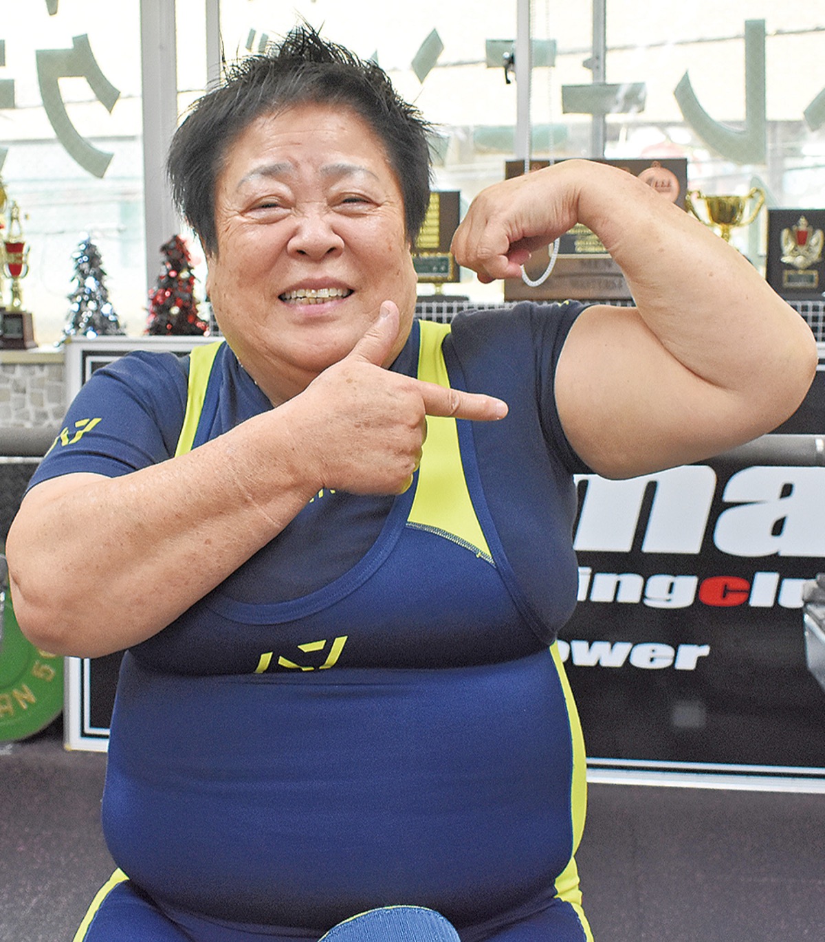 自慢の力こぶを見せる笑顔の澤さん