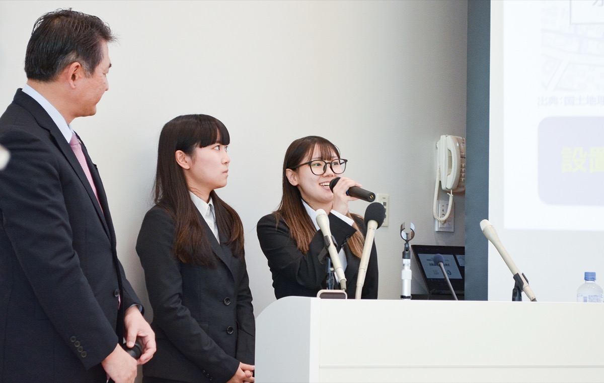 市長(左)の前で作品について解説する学生