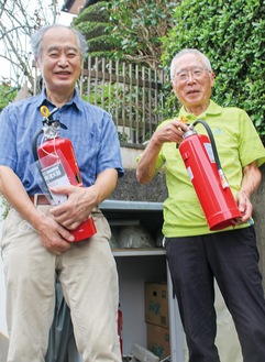 「ごみ集積場」に設置されている消火器を手にする小田嶋さん（左）と林さん