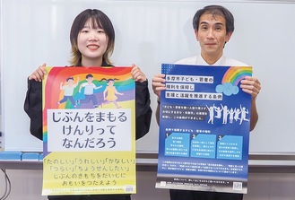 子ども用ポスターを持つ堀井さん（左）と大人用を持つ下井教授